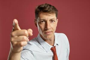 Portrait of a young brunet man posing in a studio against a red background. photo