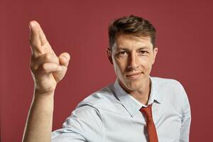 Portrait of a young brunet man posing in a studio against a red background. photo