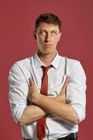 Portrait of a young brunet man posing in a studio against a red background. photo