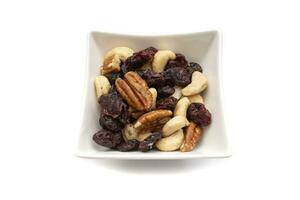 A white bowl with dried fruits and nuts, isolated on white background.Dried fruits are so called because they all have one characteristic in common,they have less than 50percent water. photo