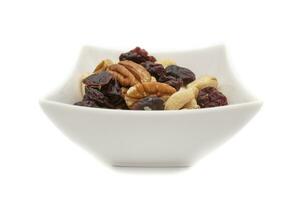 A white bowl with dried fruits and nuts, isolated on white background.Dried fruits are so called because they all have one characteristic in common,they have less than 50percent water. photo