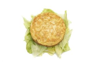 Español tortilla en parte superior de algunos lechuga hojas, aislado en blanco antecedentes. en mini versión, en el formar de un hamburguesa. foto