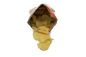 Bag of potato chips, open and front view. With potato chips inside and outside the bag. Isolated on white background. Selective focus. In Western countries, they are a very important part of the snack photo