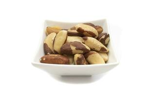 A bowl of Brazil nuts or Amazon nuts, isolated on a white background. Bertholletia excelsa is a tree of the Lecythidaceae family, native to South America, endemic to the Amazon. photo