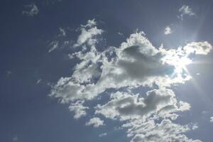 A blue sky with white clouds, coming out some rays of sun, as a background. photo