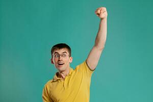 Handsome guy in a yellow casual t-shirt is posing over a blue background. photo