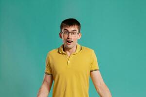 Handsome guy in a yellow casual t-shirt is posing over a blue background. photo