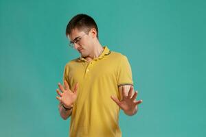 Handsome guy in a yellow casual t-shirt is posing over a blue background. photo