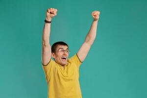 Handsome guy in a yellow casual t-shirt is posing over a blue background. photo