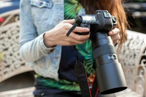 Close-up of female hands holding a professional camera. Female photographer with a professional camera. photo