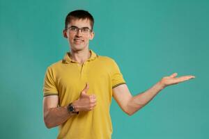 Handsome guy in a yellow casual t-shirt is posing over a blue background. photo