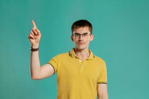 Handsome guy in a yellow casual t-shirt is posing over a blue background. photo