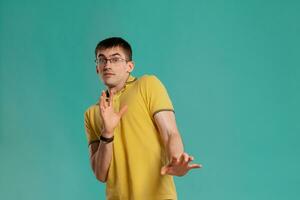 Handsome guy in a yellow casual t-shirt is posing over a blue background. photo