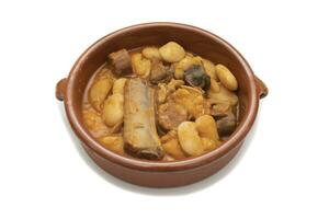 A terracotta plate with Asturian fabada, a typical Spanish bean stew, on a white background. Spanish food concept. photo