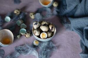 quail eggs in ceramic vases, gray feathers on the table, Easter still life with dietary eggs, diet and antioxidant photo