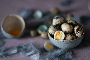 quail eggs in ceramic vases, gray feathers on the table, Easter still life with dietary eggs, diet and antioxidant photo
