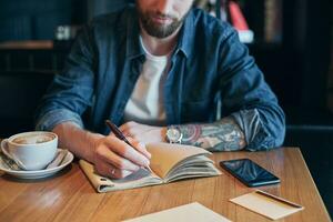 Man hand with pen writing on notebook on a wooden table. Close-up photo