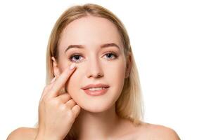 Young woman holding contact lens on index finger with copy space. Close up face of healthy beautiful woman about to wear contact lens. photo