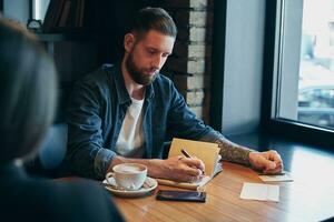 Man hand with pen writing on notebook on a wooden table. photo