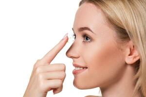 Young woman holding contact lens on index finger with copy space. Close up face of healthy beautiful woman about to wear contact lens. photo