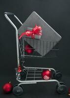 Christmas gift boxes in black paper in a shopping basket with red balls photo