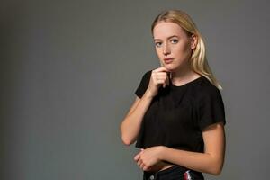 Beautiful blonde in a black t-shirt on grey background. photo