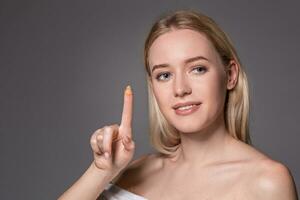 Young woman holding contact lens on index finger with copy space. Close up face of healthy beautiful woman about to wear contact lens. photo