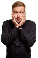 Studio portrait of gloomy european man showing boredom while leaning head on hand and standing over white background. photo