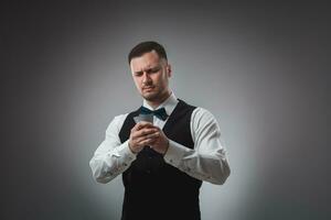 Young man in shirt and waistcoat watch his poker cards, studio shot photo