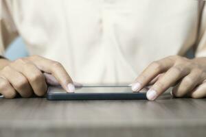 Close-up of a man's hand using a cell phone to search for information. On old wooden table, shopping or business planning concept on touchphone, male businessman using wireless device photo