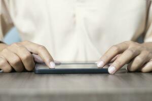 Close-up of a man's hand using a cell phone to search for information. On old wooden table, shopping or business planning concept on touchphone, male businessman using wireless device photo