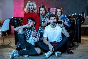 Five cheerful friends hanging out in an apartment and watching a photo