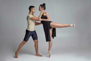 dos atlético moderno ballet bailarines son posando en contra un gris estudio antecedentes. foto