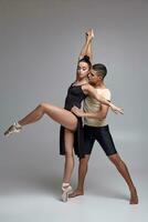 Two athletic modern ballet dancers are posing against a gray studio background. photo