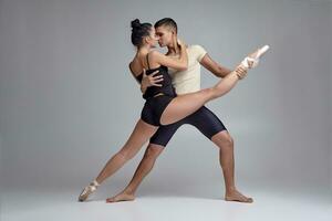 Two athletic modern ballet dancers are posing against a gray studio background. photo