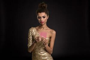 Woman winning - Young woman in a classy gold dress holding two cards, a poker of aces card combination. Emotions photo