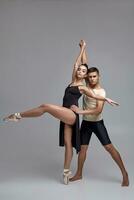 Two athletic modern ballet dancers are posing against a gray studio background. photo