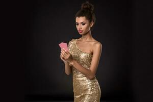 Woman winning - Young woman in a classy gold dress holding two cards, a poker of aces card combination. Emotions photo