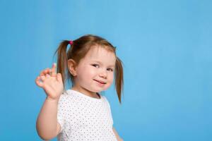 Funny kid in white T-shirt on blue background. Little pretty girl isolated on blue background. Copy space for text. photo