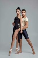 Two athletic modern ballet dancers are posing against a gray studio background. photo