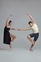 Two athletic modern ballet dancers are posing against a gray studio background. photo