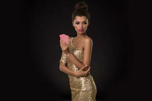 mujer victorioso - joven mujer en un de buen tono oro vestir participación dos tarjetas, un póker de ases tarjeta combinación. emociones foto