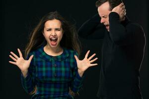 ouple having conflict, bad relationships. Angry fury woman screaming man closing his ears. photo