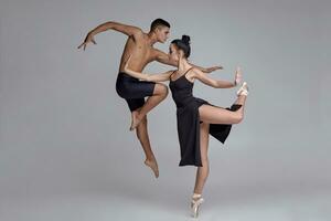 Two athletic modern ballet dancers are posing against a gray studio background. photo