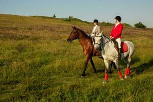 Two young women riding horse in park. Horse walk in summer photo