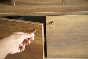 man's hand open drawer wooden in cabinet photo