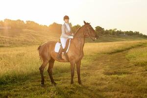 Equestrian sport. Young woman riding horse on dressage advanced test. Sun flare photo