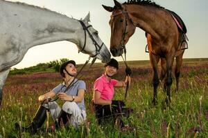 Two woman and two horses outdoor in summer happy sunset together nature photo