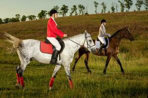 Two young women riding horse in park. Horse walk in summer photo