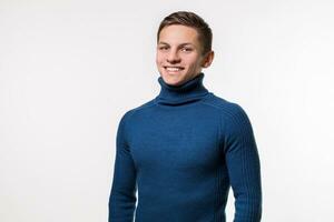 Studio shot of young man wearing blue turtleneck sweater against photo